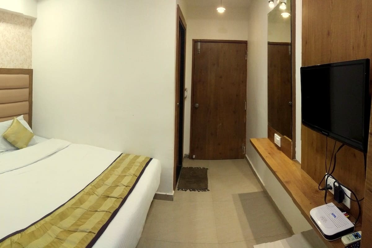 Una camera d'albergo con un letto, comodino, televisore e presa di corrente.