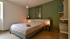 A bedroom with a bed, bedside lamps, a mirror, and a wooden floor. - Appartamento Lucia by Theater Home - with big balcony and a panoramic view (Tignale)