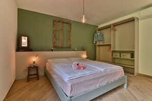 Een slaapkamer met een bed, bedlampen, een kledingkast en een spiegel aan de muur.