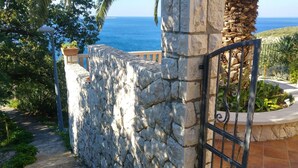 A stone wall with a metal gate, a pathway, and a view of the sea. - Private Seaside Villa Sleeps 10 With Infinity Pool (Zupa dubrovacka)