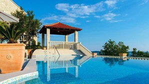A clear blue infinity pool with a stone structure and steps leading to a terrace. - Private Seaside Villa Sleeps 10 With Infinity Pool (Zupa dubrovacka)
