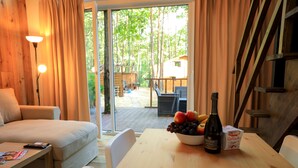 A cozy room with a wooden table, a bowl of fruit, a bottle of wine, and a couch. - Bizon Village (Piaseczno)