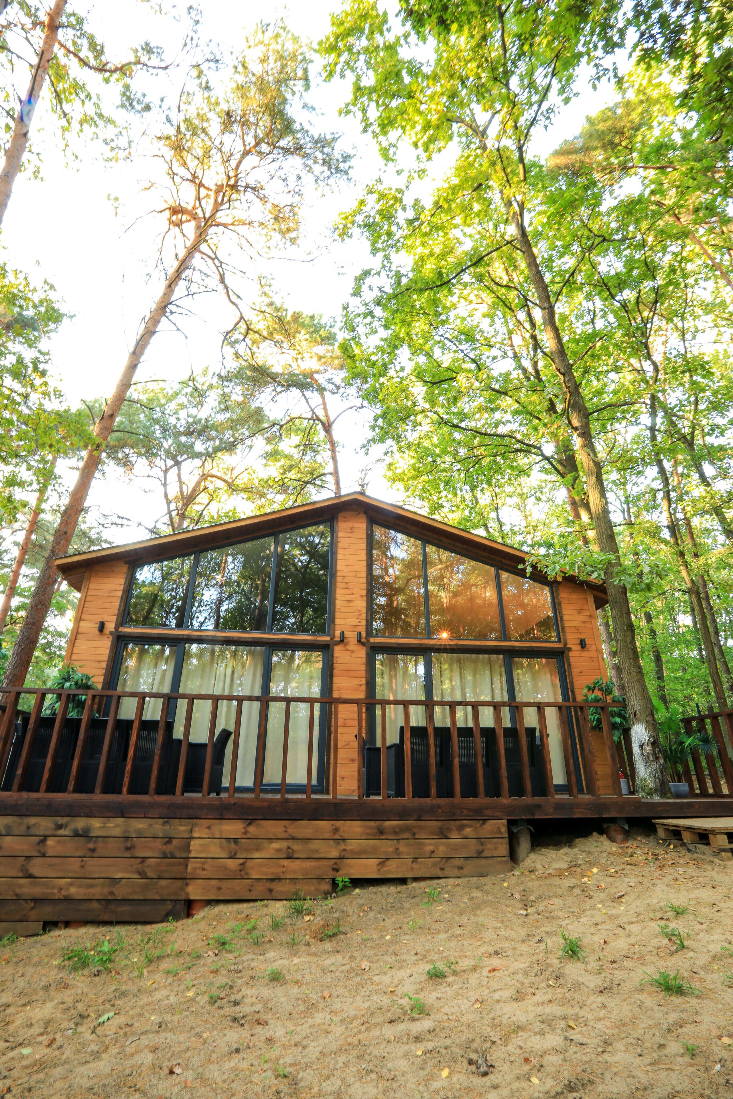 A wooden cabin with large windows, surrounded by trees.