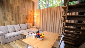 A wooden-floored living area with a sofa, a dining table with a fruit bowl, and a staircase. - Bizon Village (Piaseczno)