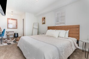 Un dormitorio ordenado con una cama grande, un escritorio y una silla.
