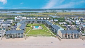 Un resort con varias construcciones, una piscina central y una zona de playa.