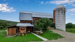A rustic barn with a silo, wooden exterior, and a gravel driveway. - Woodsy Retreat in a Quiet Corner of Cuba, with jacuzzi and a theater room (Cuba)