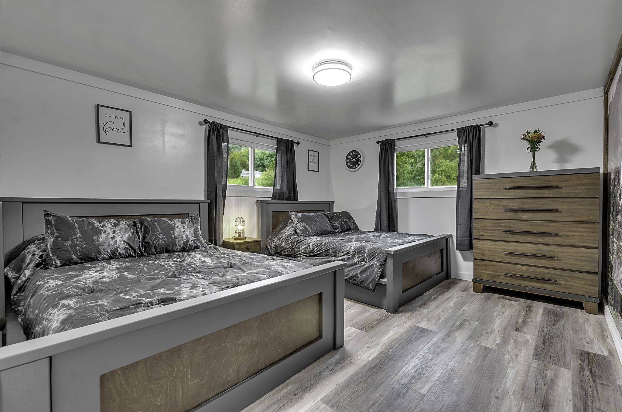 Une chambre avec deux lits, une commode et une fenêtre avec des rideaux.