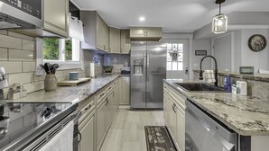 A modern kitchen with stainless steel appliances, beige cabinetry, and a marble countertop. - Woodsy Retreat in a Quiet Corner of Cuba, with jacuzzi and a theater room (Cuba)