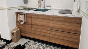Une cuisine moderne avec des armoires blanches, une hotte de cuisinière en acier inoxydable, un évier et une machine à café.