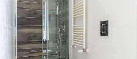 A modern bathroom with a glass-enclosed shower, a white toilet, and a bidet.