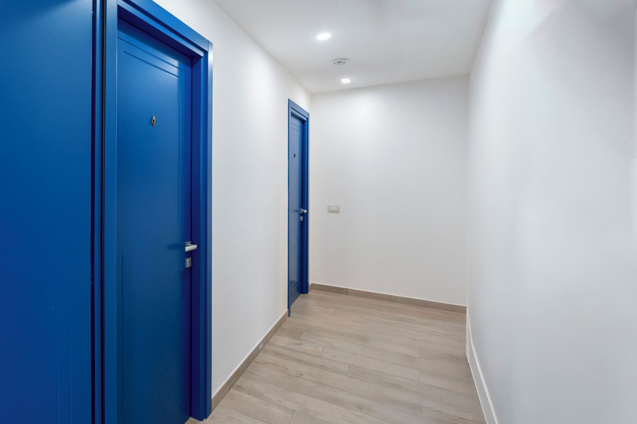 Un pasillo con puertas azules y suelo de madera.