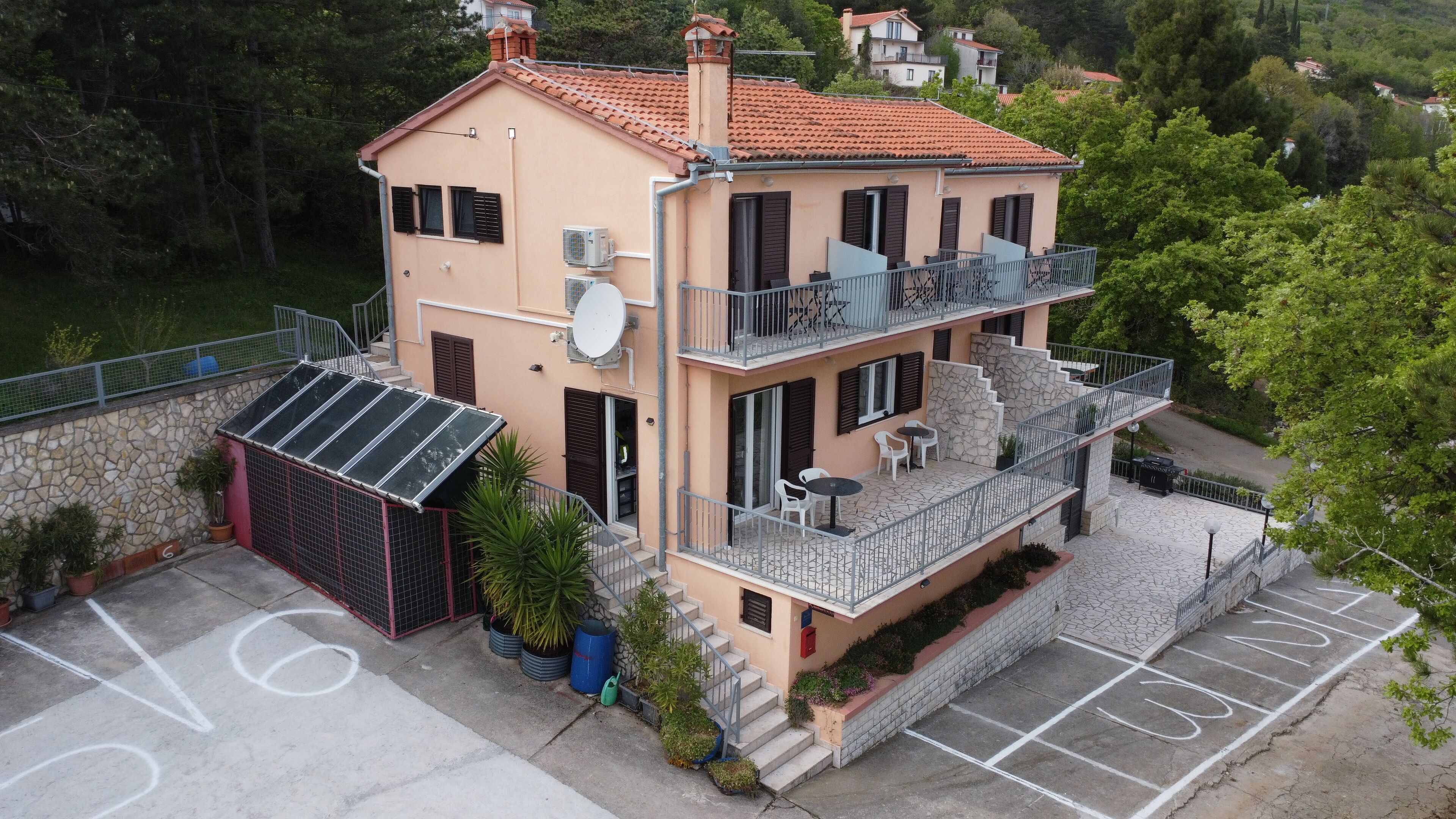 Ein zweistöckiges Gebäude mit Balkon, Satellitenschüssel und einer Steinmauer.