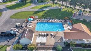 Vista aérea de una propiedad residencial con piscina, sillas de descanso y un patio cubierto.