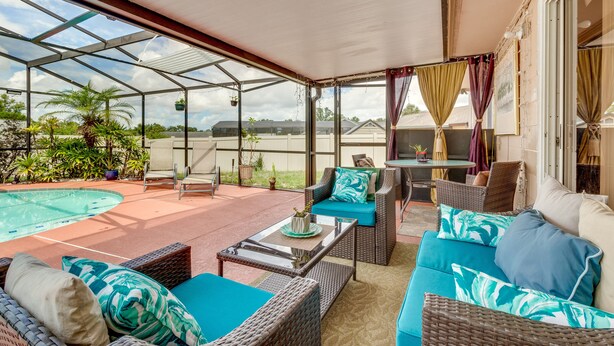 Eine überdachte Terrasse mit Gartenmöbeln, einem Pool und Blick auf die Umgebung.