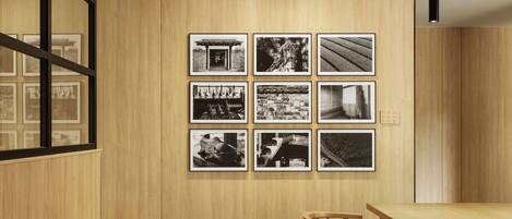 A modern interior with a wooden wall and a series of black and white photographs. There is a wooden table and chairs in the foreground.