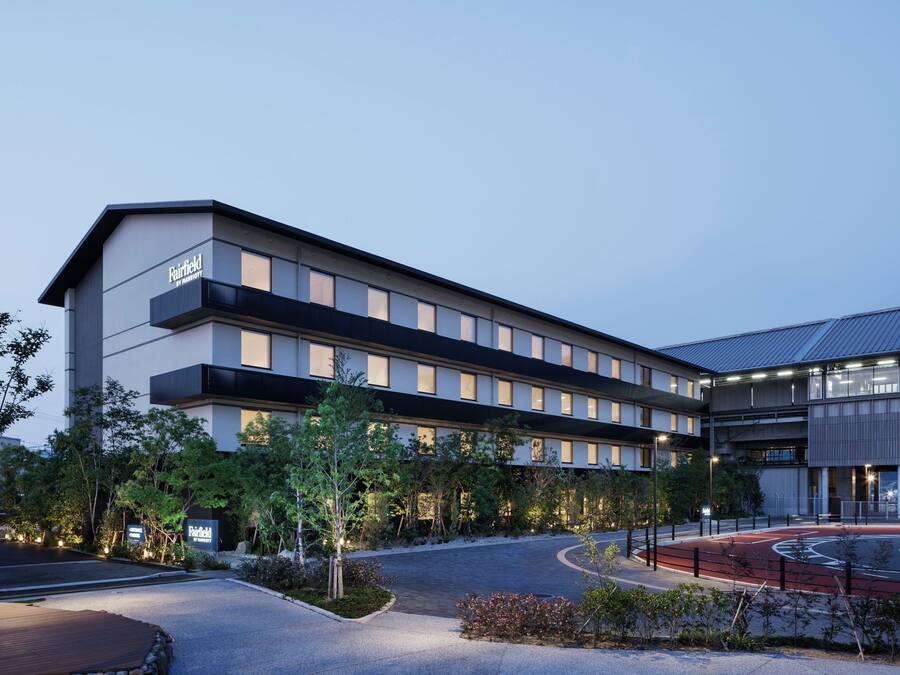 A modern hotel with a flat roof, multiple floors, and a well-lit entrance.