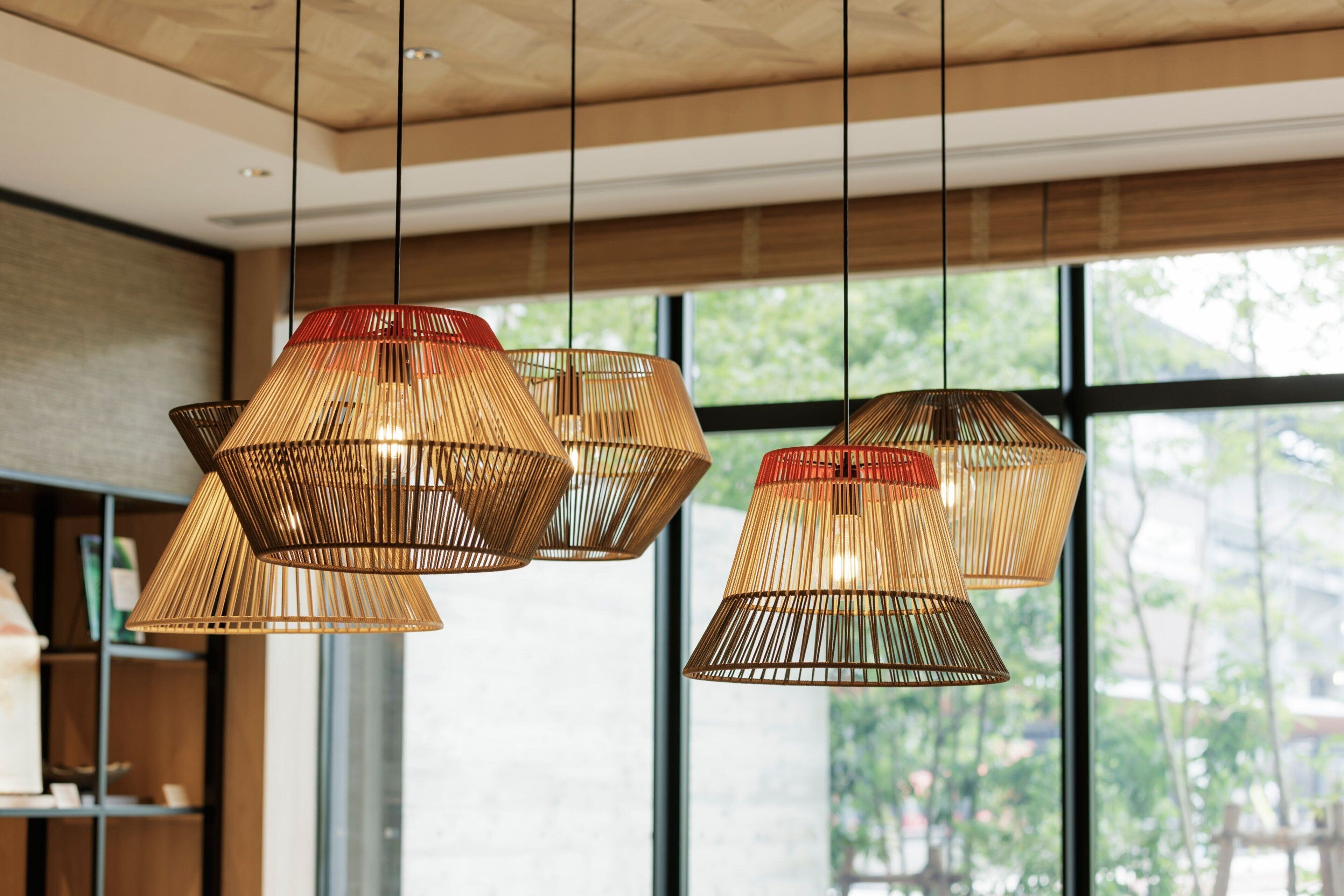 A modern interior with three hanging bamboo lamps and large windows.