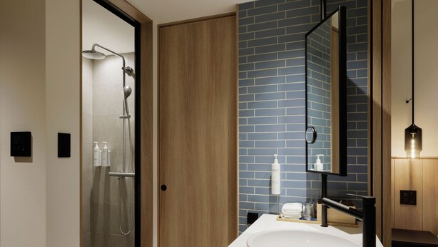 Ein modernes Badezimmer mit einer Glaskabine, einer Holztür, einer blauen Fliesenwand, einem weißen Waschbecken und einem Spiegel.