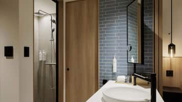 Een moderne badkamer met een glazen douchecabine, een houten deur, een blauwe betegelde wand, een witte wastafel en een spiegel.