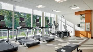 A gym with treadmills, elliptical machines, and a yoga mat.