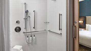 A modern bathroom with a walk-in shower, grab bars, and a towel rack.