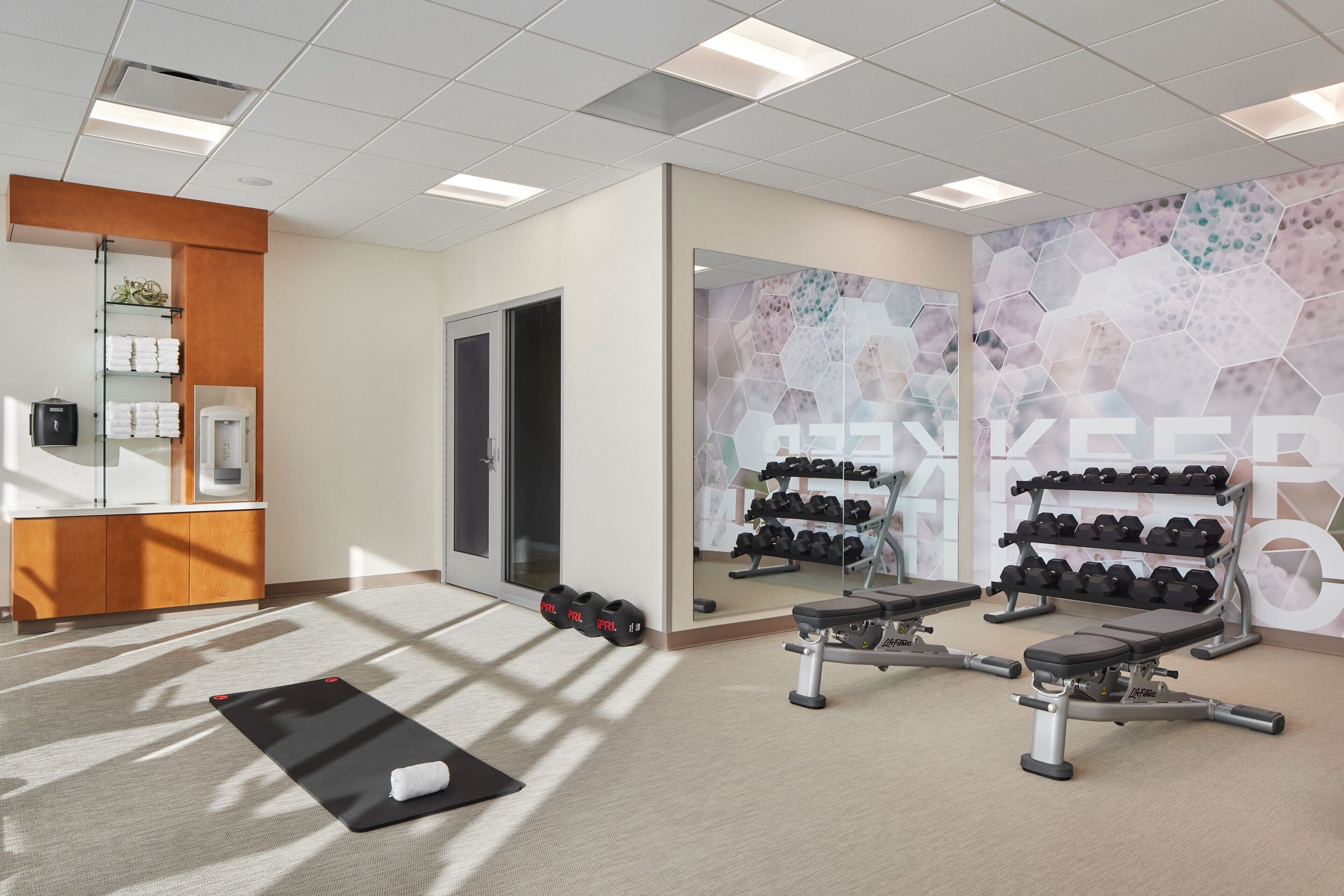 Une salle de sport équipée de matériel d’exercice, avec des serviettes et un miroir.