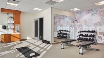 Une salle de sport équipée de matériel d’exercice, avec des serviettes et un miroir.