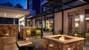 An outdoor patio area with stone seating, a fire pit, and modern furniture. - Springhill Suites By Marriott Frederica (Frederica)