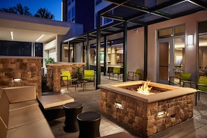 An outdoor patio area with stone seating, a fire pit, and modern furniture. - Springhill Suites By Marriott Frederica (Frederica)