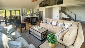 A spacious living area with a high ceiling, a dining area, and a kitchen.