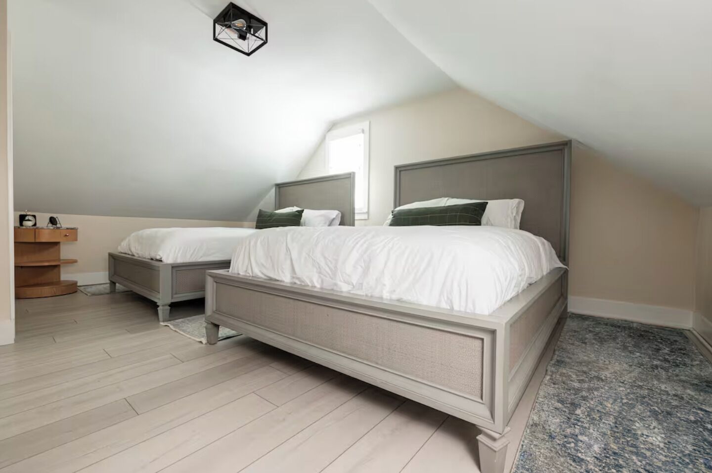 Un dormitorio con dos camas, un aparador de madera y una lámpara en el techo.