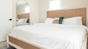 Quarto de hotel com uma cama grande, um espelho e uma janela.