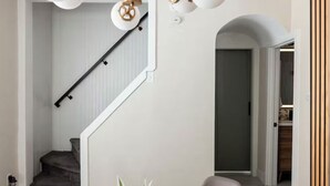 Uma escadaria com design moderno, um candeeiro no teto e uma porta que dá para outro espaço.