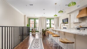 Une cuisine moderne avec un coin bar, un plancher en bois et une vue sur la ville grâce à de grandes fenêtres.