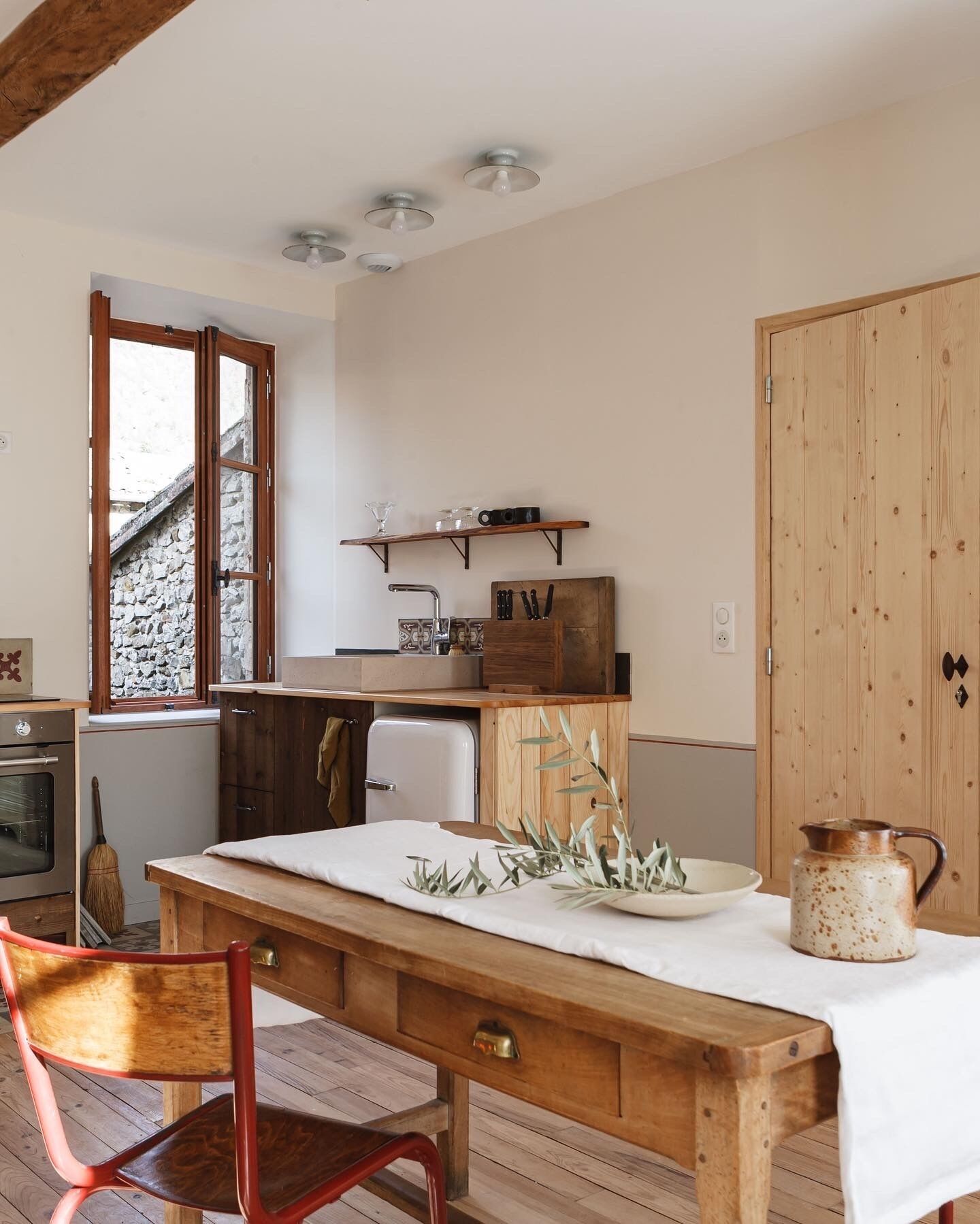 Une cuisine chaleureuse avec des meubles en bois, une table à manger recouverte d’une nappe blanche et une esthétique rustique.