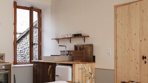 A cozy kitchen with wooden cabinets, a dining table with a white tablecloth, and a rustic aesthetic.