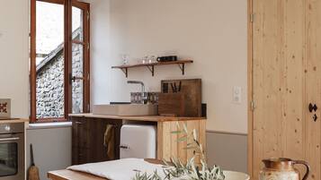 Une cuisine chaleureuse avec des meubles en bois, une table à manger recouverte d’une nappe blanche et une esthétique rustique.