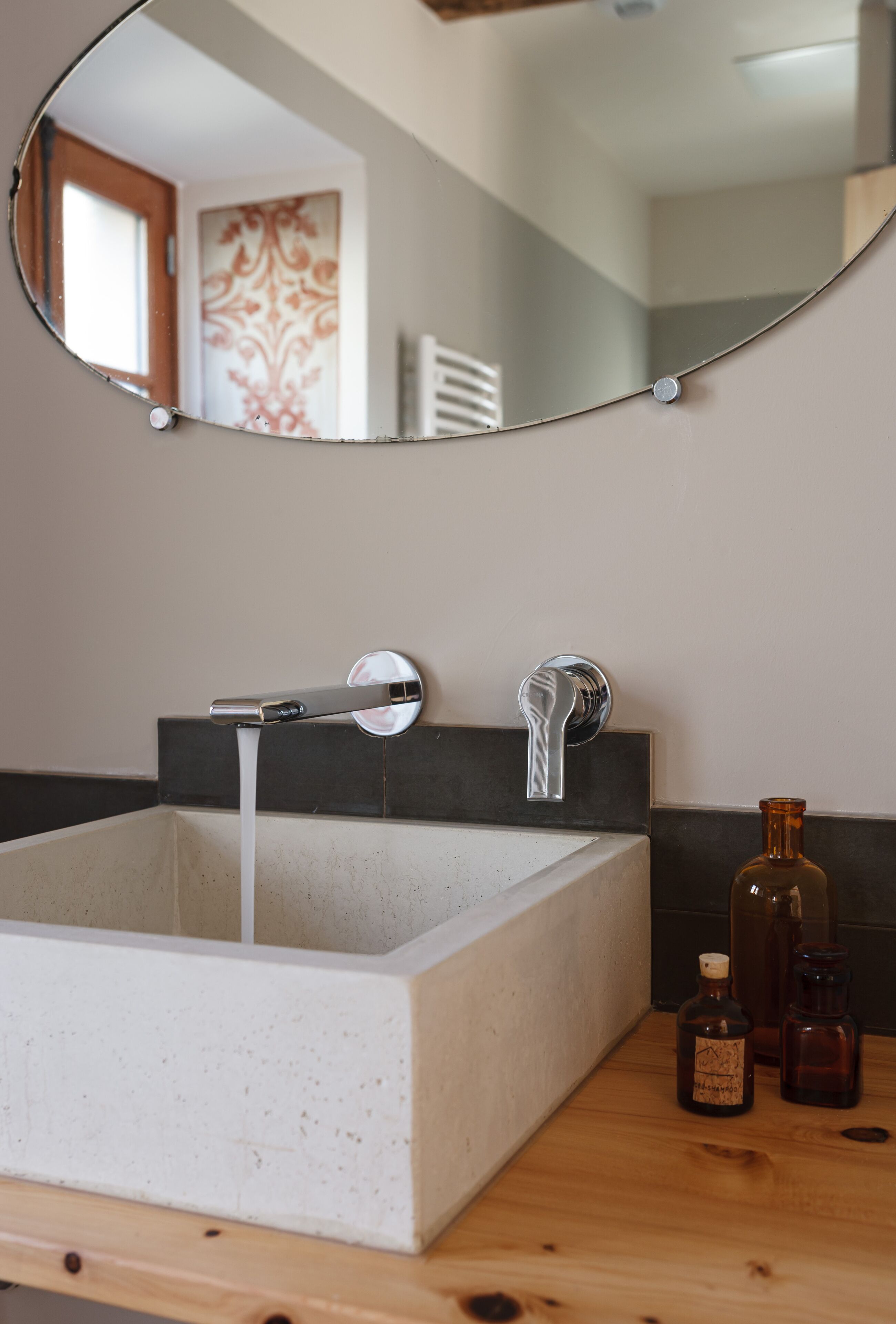 A bathroom with a rectangular sink, two faucets, and a mirror above.
