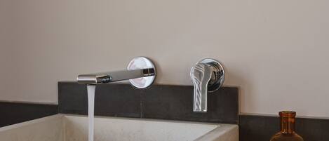 A bathroom with a rectangular sink, two faucets, and a mirror above.