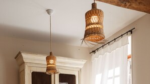 A dining area with a wooden table, chairs, a cabinet with glass doors, and hanging wicker lamps.