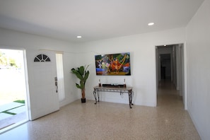 Experience the serene ambiance of this stylish space, featuring a vibrant abstract art piece, lush greenery, and a door leading to an outdoor area.
