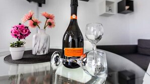 A bottle of Valdobbiagene wine on a glass table with a wine glass beside it, surrounded by decorative flowers and a marble vase.