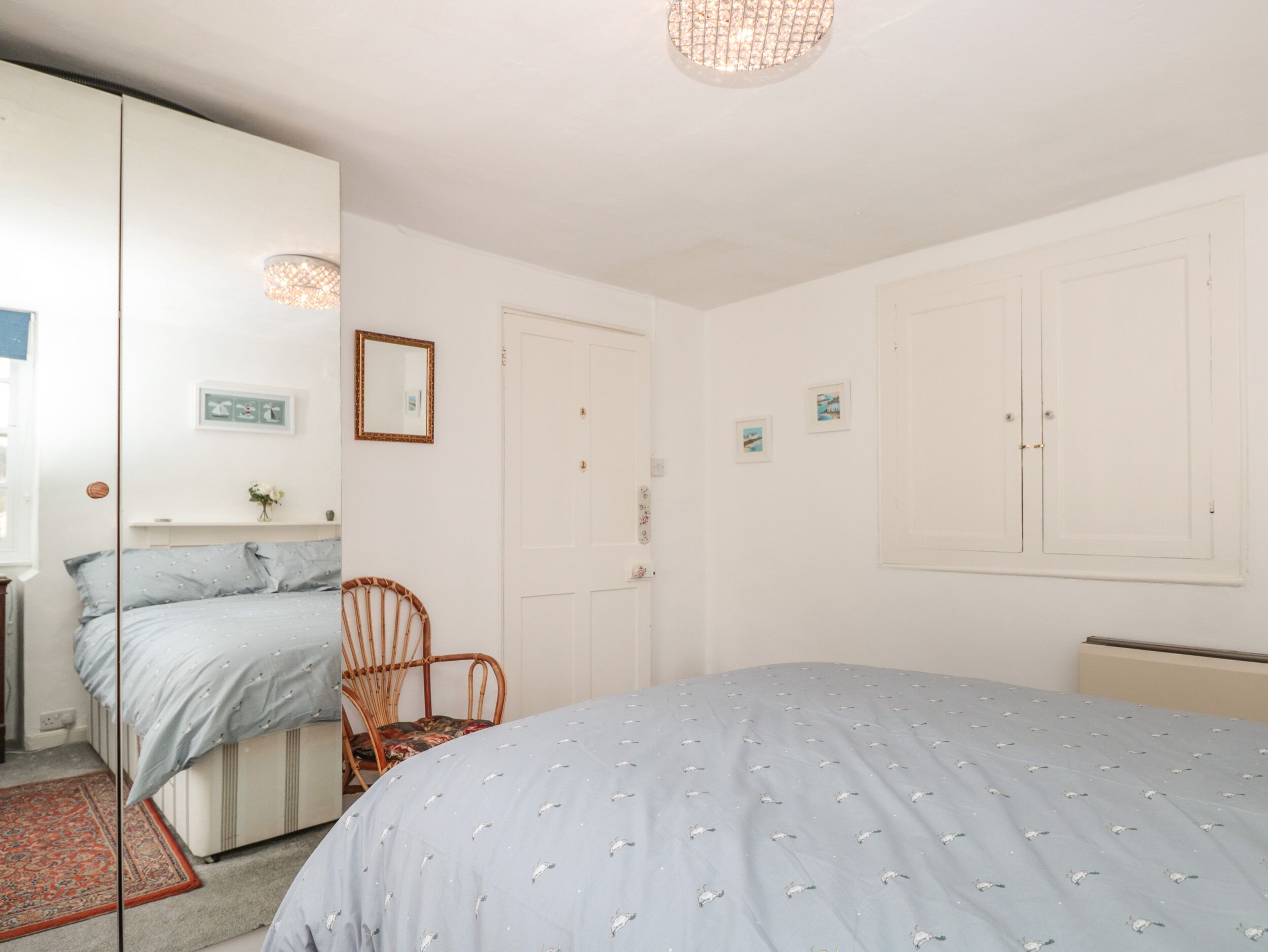 A bedroom with a bed, a chair, a wardrobe, and a mirror.