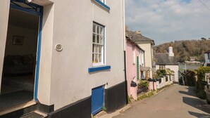 En smal gade med traditionelle bygninger, heriblandt en hvid bygning med blå detaljer og en pink bygning med grønne skodder.