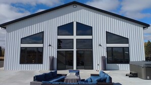 Un bâtiment moderne doté de grandes fenêtres et d’un espace extérieur aménagé avec des sièges, protégé par un auvent.