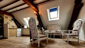 Un acogedor dormitorio en el ático con comedor, pisos de madera y una cocina al fondo.