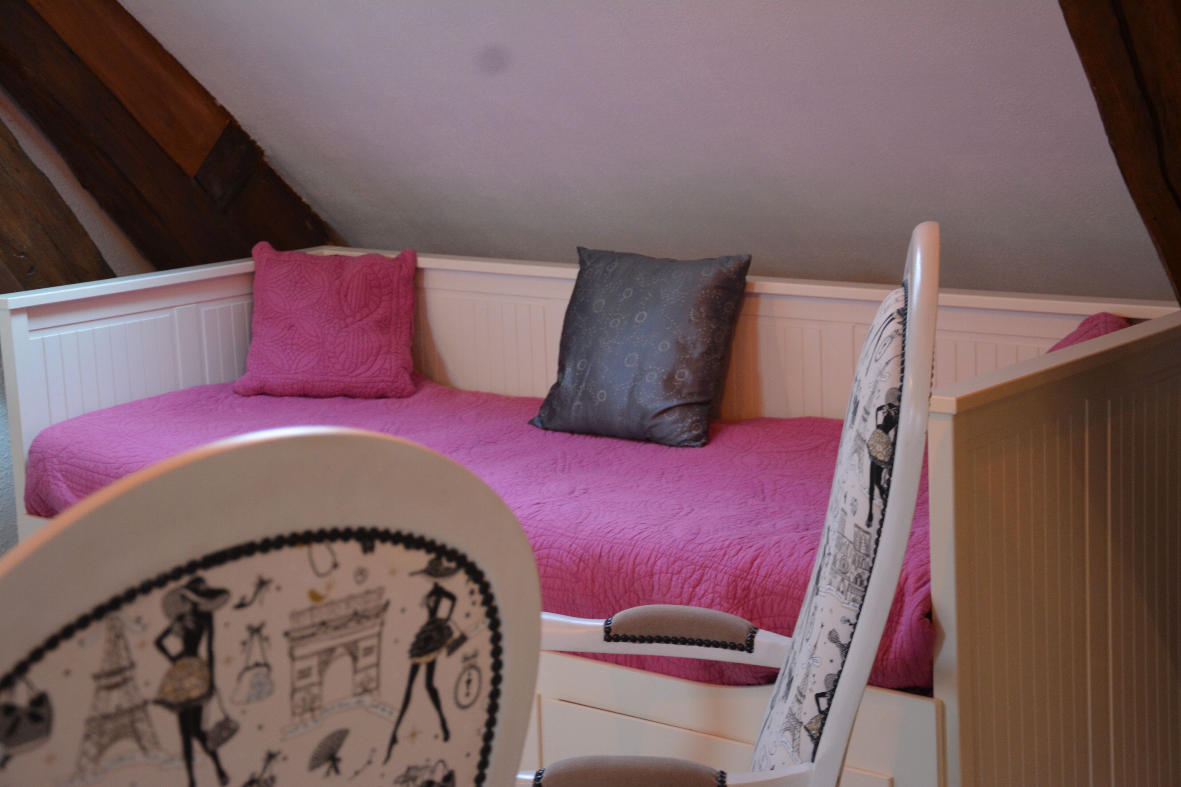 Ein Schlafzimmer mit einem Bett, Kissen und einem Sessel.