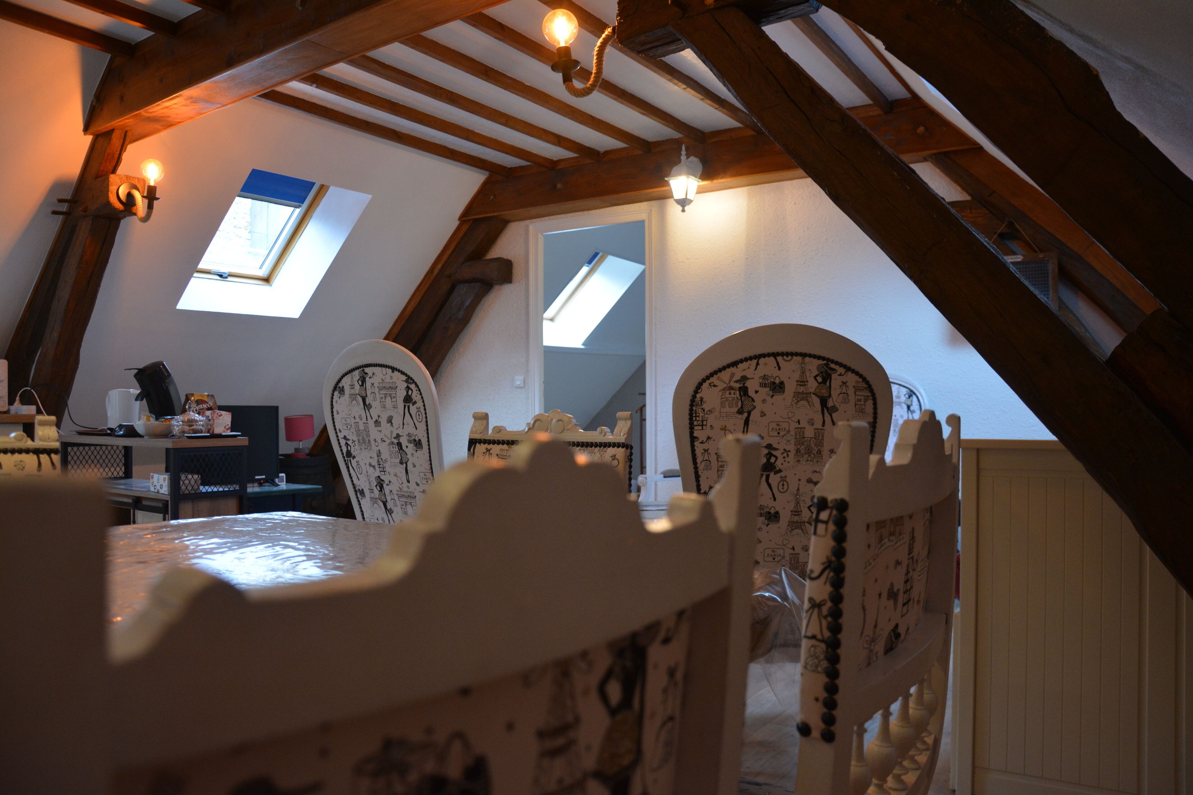 A cozy attic room with a sloped ceiling, two skylights, and a dining table with chairs.