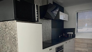 A modern kitchen with a microwave, oven, and built-in cabinets. - Pour 4 Pers Plein Soleil, Gd Terrasse sur Toiture (L'Aiguillon-la-Presqu'île)